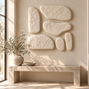 Puede incluir: Una instalación de arte mural compuesta por cinco paneles beige de formas orgánicas y texturizadas que recuerdan a la piedra. Las piezas presentan un acabado de superficie rugoso y poroso, montadas sobre una pared beige sobre un banco de piedra.