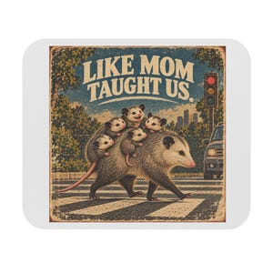 Könnte beinhalten: Ein rechteckiges Mauspad mit einer Illustration im Vintage-Stil, die ein erwachsenes Opossum zeigt, das drei Junge auf dem Rücken trägt und eine Straße überquert. Der Text "LIKE MOM TAUGHT US." steht darüber neben einer Ampel und einem Auto.