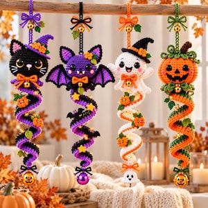 May include: Four hanging crochet decorations featuring a black cat, a purple bat, a white ghost, and an orange pumpkin. Each figure has a spiral tail adorned with small pumpkins, stars, or leaves, and a small bell at the top and bottom.