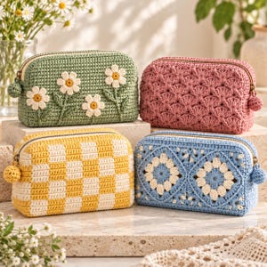 May include: Four rectangular crochet pouches with zip closures and small pom-pom pulls. One is sage green with white daisy appliqués, one is dusty rose with a shell stitch pattern, one is yellow and white checkered, and one is blue with white floral motifs.