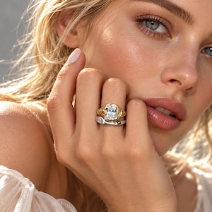 May include: A two-piece ring set featuring a gold-toned band with a large, rectangular, clear faceted stone and a separate, smooth, silver-toned band worn together on the finger, showcasing a mixed-metal aesthetic with organic textures.