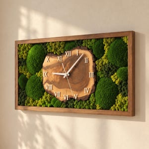 May include: A rectangular wall clock featuring a natural wood slice center with visible grain and white Roman numerals. The clock face is surrounded by dense, textured green moss in various shades, all encased within a simple brown wooden frame.