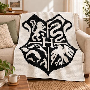Peut inclure: Une couverture en crochet rectangulaire présentant un grand motif noir et blanc de l'écusson de l'école Poudlard. Le motif affiche une lettre H centrale entourée d'un lion, d'un serpent, d'un blaireau et d'un aigle, dans un style bicolore.