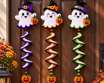 May include: Three crocheted ghost wall hangings, each wearing a witch hat and holding a small orange pumpkin. Below each ghost is a long, spiraling, multi-colored crochet tail ending in a single orange jack-o'-lantern and colorful beads.