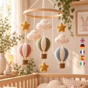 Può includere: Una giostrina sospesa per la cameretta con una cornice circolare in legno ed elementi all'uncinetto appesi a fili bianchi. La giostrina include tre mongolfiere all'uncinetto nei colori rosa polvere, verde oliva e blu, oltre a nuvole bianche e stelle gialle.