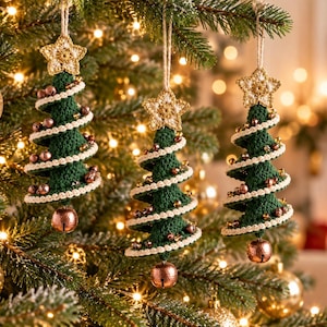 May include: Three hanging Christmas tree ornaments made of dark green crochet yarn. Each tree features a spiral of cream-colored crochet trim, small metallic copper-colored beads, and a single copper bell at the base, topped with a crocheted star.
