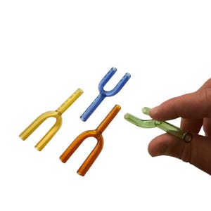 May include: Four small, U-shaped glass tubes in yellow, blue, orange, and light green. Each piece features a single stem extending from a curved, dual-pronged body. The glass is translucent and smooth, with a hollow interior visible at the ends.