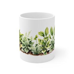 May include: White ceramic mug with a green and brown illustration of a row of leafy plants around the entire mug.