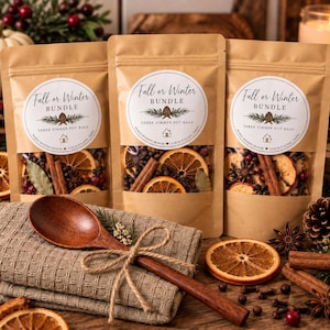 Puede incluir: Tres bolsas de papel marrón etiquetadas Fall or Winter BUNDLE THREE SIMMER POT BAGS que contienen rodajas de naranja secas, ramas de canela y especias. Una cuchara de madera está atada con cordel a una servilleta de tela beige.