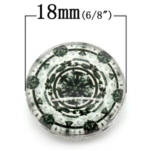 May include: A round, glass button with a black and white design. The button is 18mm (6/8 inches) in diameter and features a circular pattern with a central snowflake design.