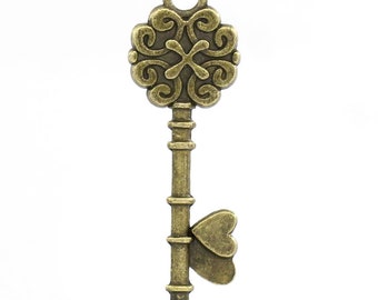 May include: Antique gold-toned key charm with a decorative heart-shaped charm attached to the bottom. The key has a detailed ornate design on the top.