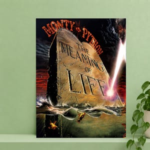 Op de afbeelding: Een rechthoekige poster met een stenen tablet met de tekst MONTY PYTHON THE MEANING OF LIFE. Het tablet is gedeeltelijk ondergedompeld in donker water met kleine vissen onder het oppervlak, tegen een donkere, dramatische lucht met licht.