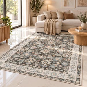 May include: A rectangular area rug featuring a dark charcoal background with a repeating floral and geometric pattern in shades of light blue, cream, and soft pink, framed by a wide cream-colored border with a delicate botanical motif.