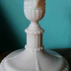 May include: A pink glass candlestick with a fluted design and a decorative base.