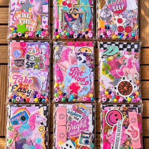 May include: Nine clear plastic pouches filled with colorful paper ephemera, stickers, and loose beads. Each pouch features vibrant designs including unicorns, cherries, disco balls, smiley faces, and text like Be Your Best Self and Rock Star.