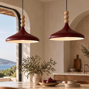 May include: Two pendant lights featuring wide, deep red metal shades with a matte finish. Each light is suspended by a black cord accented with three stacked, light-colored wooden spheres above the shade, providing a clean, functional design.