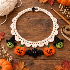 May include: A cream-colored crocheted collar necklace featuring five dangling charms: two green-faced witch heads with black hats, two orange jack-o'-lantern pumpkins, and one black bat with orange eyes. The collar fastens with a single black button.