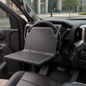 May include: A black, foldable steering wheel desk tray featuring a diamond plate texture on both the vertical back panel and the horizontal work surface. The tray is securely mounted onto the steering wheel of a vehicle interior.