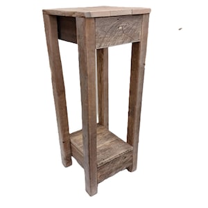 May include: A rustic wooden plant stand with a single drawer and a lower shelf. The stand is made of reclaimed wood and has a natural, weathered finish.