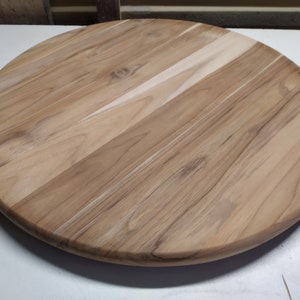 May include: A round wooden table top with a natural wood finish. The top is made of several pieces of wood that have been joined together to create a unique pattern.