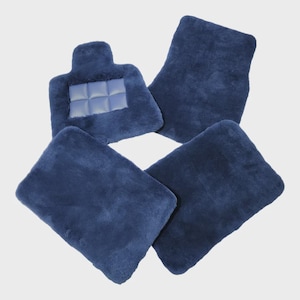 Può includere: Un set di quattro tappetini per auto in peluche blu scuro. Tre tappetini sono rettangolari con una consistenza morbida e soffice, mentre uno presenta una forma distinta con un poggiatacco a griglia integrato al centro.