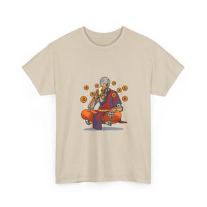 May include: A beige short-sleeve t-shirt featuring a graphic print of a robotic figure in a meditative pose, wearing orange and blue robes, eating a banana, and surrounded by floating circular orange icons with the Om symbol printed on them.