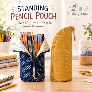 Peut inclure: Deux trousses à crayons verticales, une bleu marine à pois blancs et une jaune moutarde à pois blancs. La trousse bleu marine est ouverte, révélant un intérieur crème à petits points, remplie de divers crayons de couleur et stylos.
