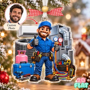 Op de afbeelding: Een gepersonaliseerd foto-ornament met een cartoon HVAC-technicus in een blauw uniform en pet, die een duim omhoog geeft. Het personage is omringd door airconditioningapparatuur, een roze koelmiddeltank, een blauwe gereedschapskist en slangen.