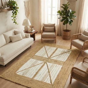 May include: A rectangular area rug featuring a natural jute border and a central panel of woven white fibers. The design includes geometric triangular patterns formed by jute strips overlaid on the white sections, creating a textured contrast.