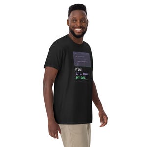 May include: A black short-sleeve t-shirt featuring a graphic of a computer terminal window with code and the text "FINE. I'LL BUILD MY OWN." The text is displayed in white, purple, and green, with a blinking cursor underscore at the end.