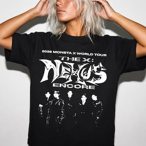 May include: A black short-sleeve t-shirt featuring white graphic text that reads 2026 MONSTA X WORLD TOUR THE X: NEXUS ENCORE. Below the text is a black and white photographic print of five individuals standing in a row, wearing dark clothing.