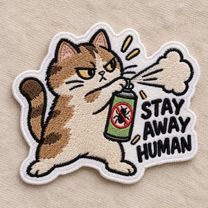 May include: An embroidered patch featuring a brown and white tabby cat with an angry expression holding a green spray can. The can displays a red circle with a black insect inside. The text STAY AWAY HUMAN is embroidered in black next to the cat.