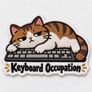 May include: An embroidered patch featuring a brown and white tabby cat with a grumpy expression lying on a gray computer keyboard. The text "Keyboard Occupation" is stitched in black below the keyboard, accented by small yellow lines on each side.