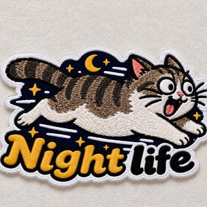 May include: An embroidered patch featuring a brown and white tabby cat running across a dark blue background with a yellow crescent moon and stars. The text Night life is embroidered in yellow and black letters at the bottom of the patch.