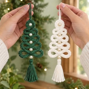 May include: Two crocheted Christmas tree ornaments, one in dark green and one in white. Each tree features a series of stacked loops, a central vertical column of small white faux pearls, and a matching yarn tassel hanging from the bottom.
