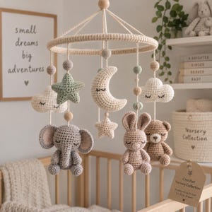 Può includere: Una giostrina per culla all'uncinetto con una struttura circolare e figure in peluche pendenti, tra cui un elefante grigio, un coniglio beige, un orso marrone, una stella verde salvia, una luna crescente e due nuvole bianche, appese a fili color crema.