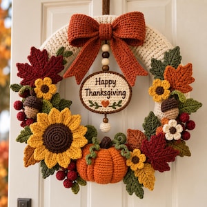 Könnte beinhalten: Ein Häkelkranz mit einer großen orangefarbenen Schleife, einem zentralen ovalen Schild mit der Aufschrift Happy Thanksgiving, einem Kürbis, Sonnenblumen, Ahornblättern und Eicheln. Der Kranz besteht aus cremefarbenem Garn und herbstlichen Häkelelementen.
