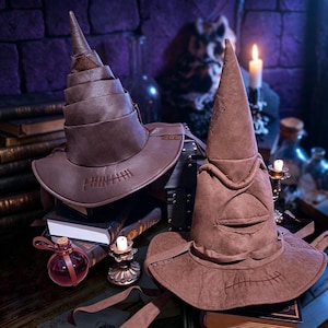 May include: Two brown pointed hats with wide brims and stitched detailing. One hat features a spiraled, layered cone design, while the other has a prominent folded crease resembling a mouth. Both hats are made of a matte, textured material.