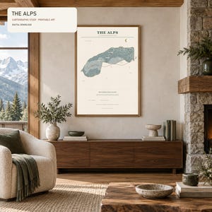May include: A vertical rectangular wall art print titled THE ALPS featuring a detailed cartographic study of the mountain range in shades of blue and green on a cream background, displayed in a thin wooden frame with black text and symbols.