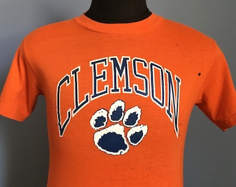 May include: Orange t-shirt with a white "CLEMSON" graphic and a blue paw print.