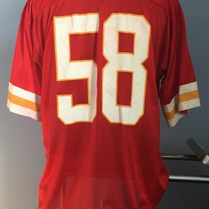 May include: Red jersey with white and gold trim. The number 58 is printed on the back in white with a gold outline.