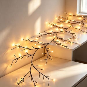 Könnte beinhalten: Eine dekorative Lichterkette in Form von dunkelbraunen Baumzweigen. Die flexible, zweigartige Struktur verfügt über zahlreiche kleine, warmweiße LED-Lichter an den Enden der Äste, die einen leuchtenden Effekt erzeugen.