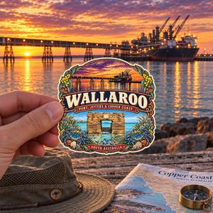 May include: A die-cut sticker featuring a sunset view of the Wallaroo jetty and a large ship. The text reads WALLAROO PORT, JETTIES & COPPER COAST SOUTH AUSTRALIA. The design includes illustrations of blue crabs, seashells, and yellow flowers.