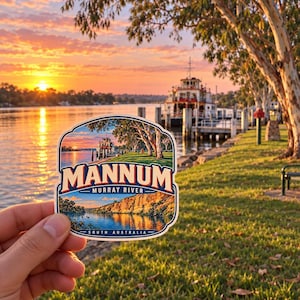 May include: A die-cut sticker featuring a scenic landscape of the Murray River in Mannum, South Australia. The design displays a riverboat at sunset, golden light reflecting on the water, and the text MANNUM MURRAY RIVER SOUTH AUSTRALIA.