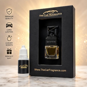 May include: A black rectangular box with gold text reading THE CAR FRAGRANCE and a website URL, containing a small glass car air freshener bottle with a black cap and hanging cord. A white plastic refill bottle with a black label is placed beside it.