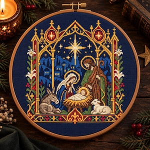 Puede incluir: Un bastidor de madera circular que contiene un diseño de punto de cruz de una escena de natividad. La imagen muestra una estrella central, un pesebre con un bebé, dos figuras, un burro y un cordero, enmarcado por un arco gótico dorado y rojo.