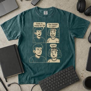 Può includere: Una t-shirt a maniche corte color verde acqua scuro con una grafica a fumetti a quattro riquadri in inchiostro color crema. I fumetti contengono il testo: Code is ready for QA, You tested it, right?, e right?