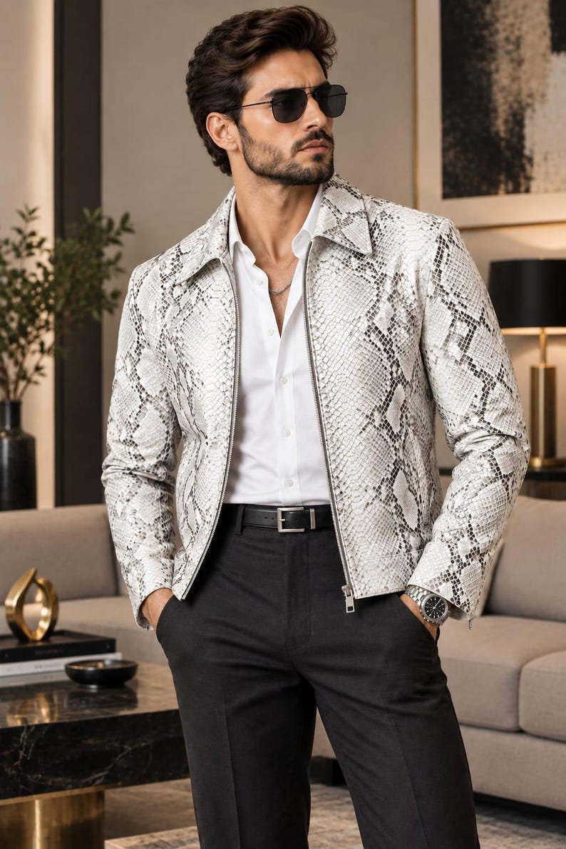 May include: A white and gray snakeskin-patterned jacket with a pointed collar and a full-length front zipper. The jacket is worn over a crisp white button-down shirt, paired with black trousers, a black leather belt, and dark sunglasses.
