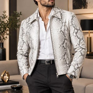 May include: A white and gray snakeskin-patterned jacket with a pointed collar and a full-length front zipper. The jacket is worn over a crisp white button-down shirt, paired with black trousers, a black leather belt, and dark sunglasses.