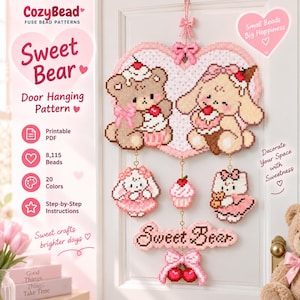 May include: A fuse bead door hanging pattern featuring a large heart with a brown bear and a cream-colored bunny, both holding desserts. Below are three smaller hanging charms, a cupcake, and a sign reading Sweet Bear with a cherry bow.
